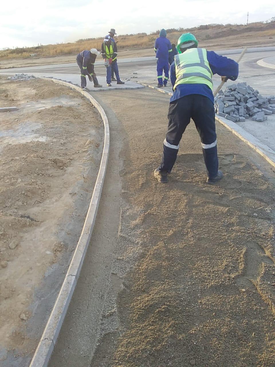 Worker installing and finishing concrete road curbs